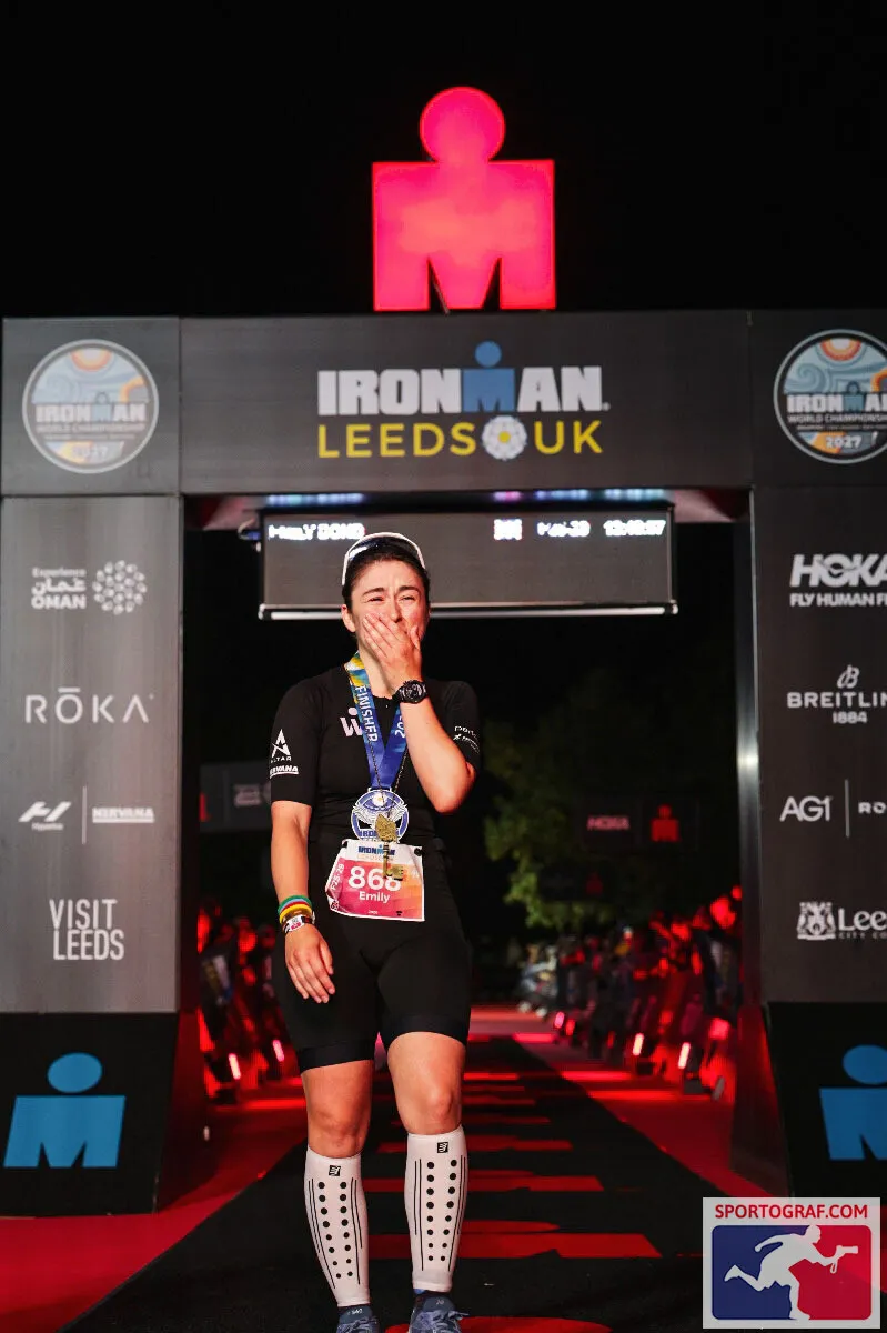 Emily Bond reacting emotionally beneath the IRONMAN Leeds finish arch