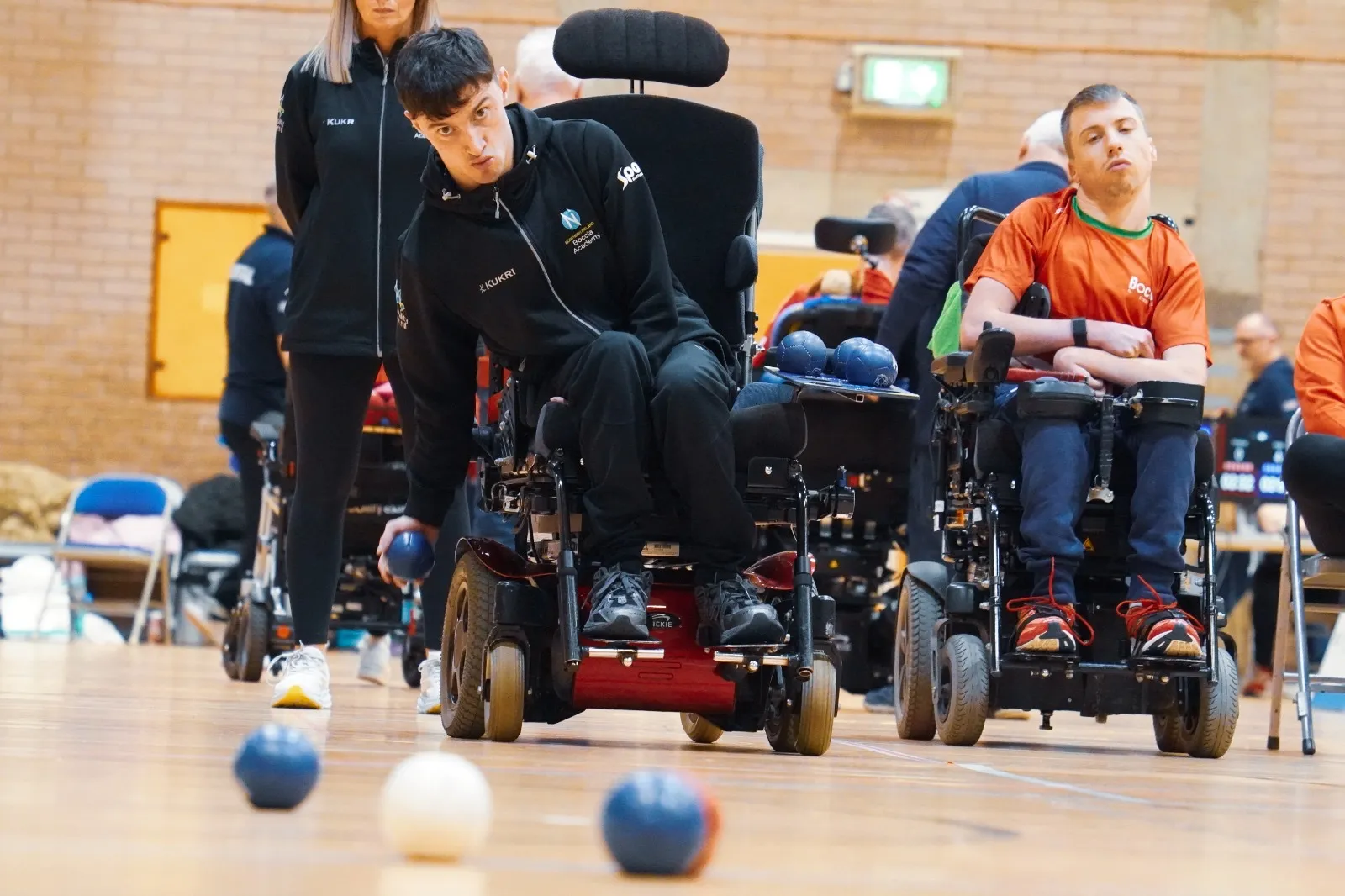 Two NI boccia athletes facing off across the court, with red, blue and white balls in the foreground