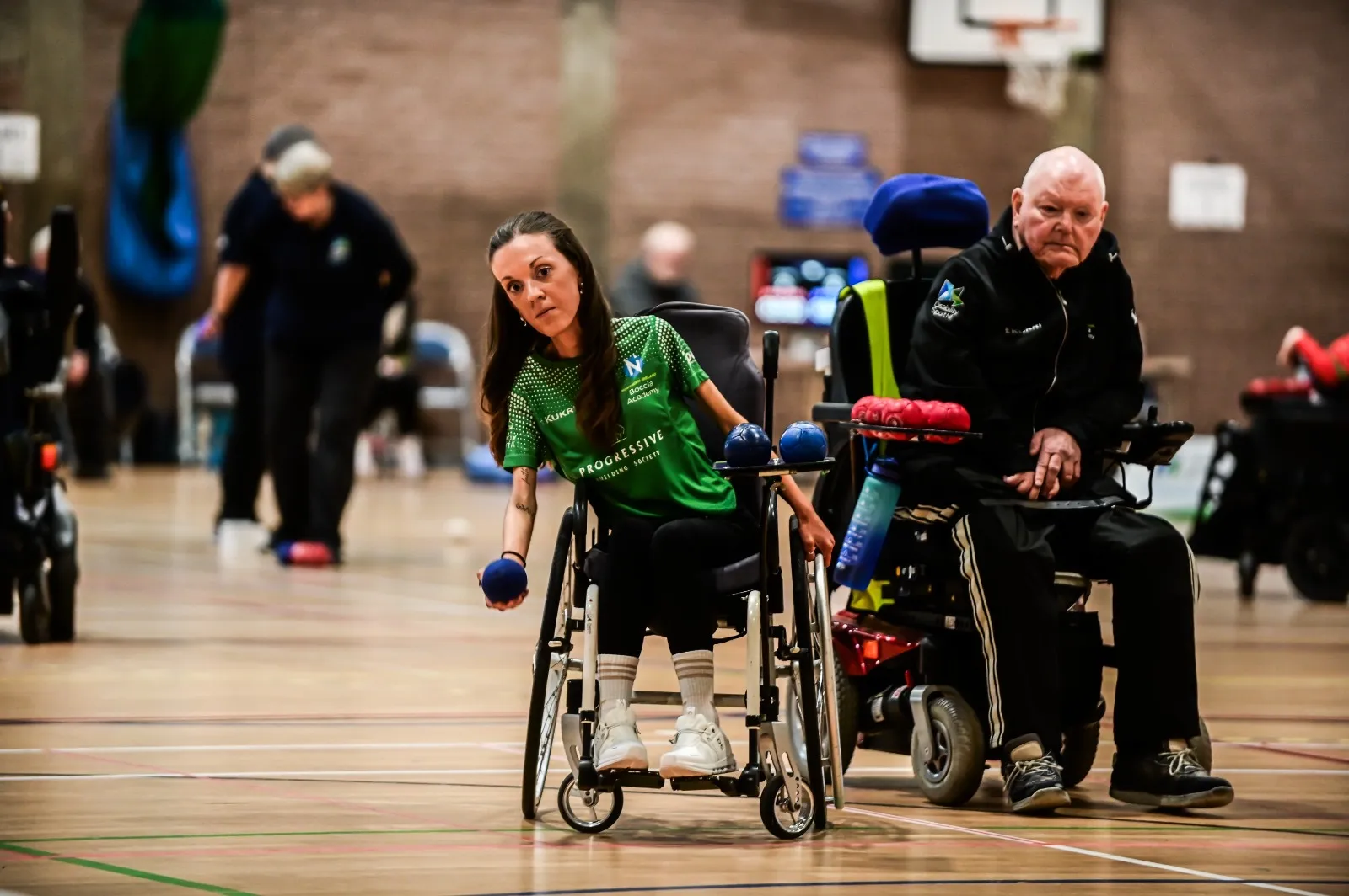 A Northern Ireland boccia athlete in a green Progressive jersey lines up a throw during an NI Boccia League match