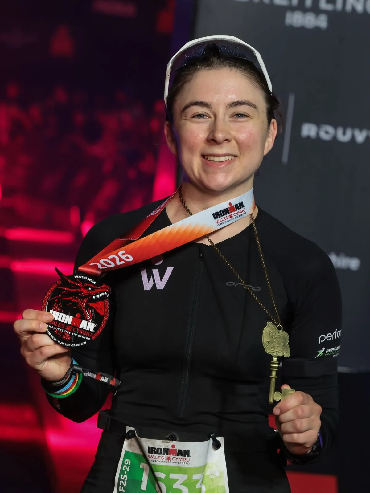 Emily Bond holding her medal and ceremonial key after completing IRONMAN Wales